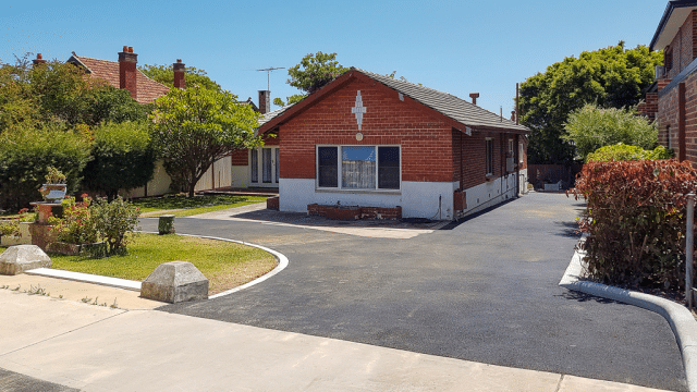 completed asphalt driveway in front of brown brick house